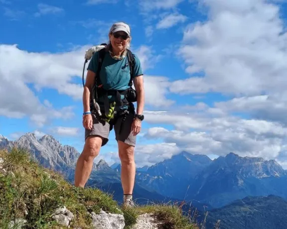 A woman standing on a mountain peak with a backpack.