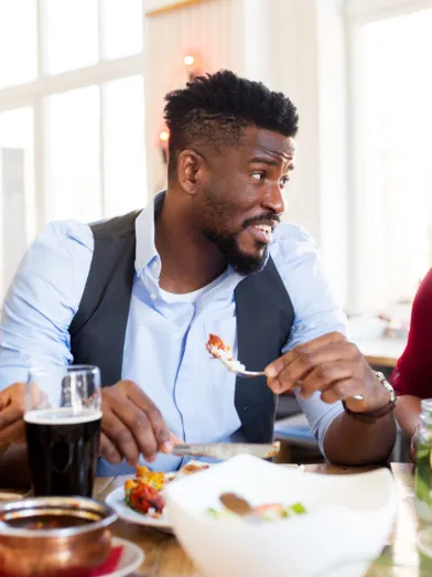 A group sit eating dinner while a couple give each other looks. 